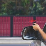 Woman in car, hand using remote control to open the auto gate when arrived home. The electric door, automatic garage, house remote controlled and security system concept.