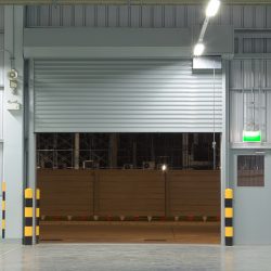 Open shutter door interior and concrete floor, night time. Rolling Steel Doors, Motor Operators, Hollow Metal Doors and Hardware, Holzer Commercial Doors, Pipe Bollards