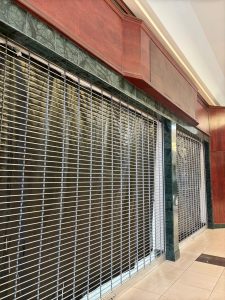 Shuttered,Storefront,With,Metal,Security,Grille,At,Dead,Shopping,Mall